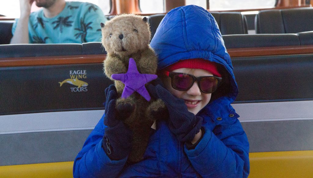A child hugs a sea otter stuffie on board 4 Ever Wild.