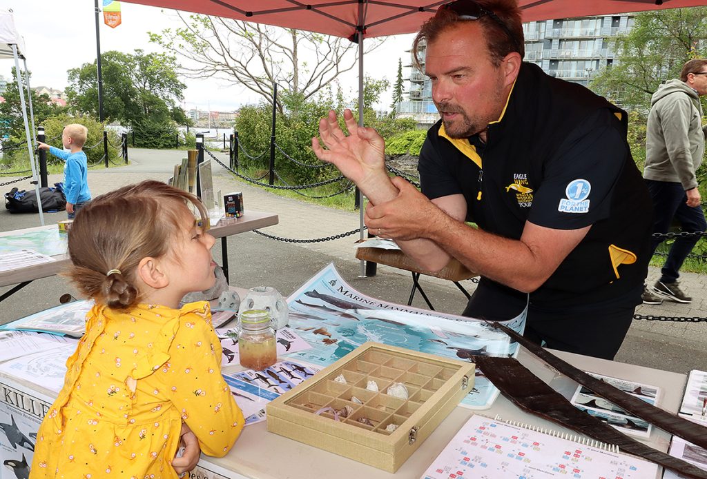 Eagle Wing co-oweer Brett shows a young girl at World Oceans Day how barnacles feed